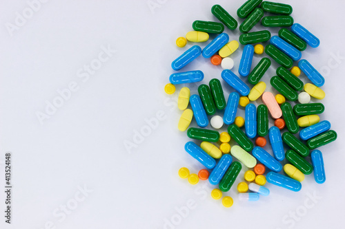 Pharmaceutical colorful pills and capsules on white background. A large number of tablets on the surface. The concept of modern treatment, pharmacy, healthcare. Empty place for text. Top view. 