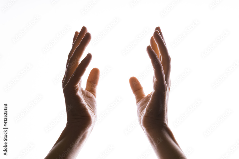 Hands make magic, or pray that the light falls from above on hand. Radiance between the palms. Gestures, isolated on white, contour lighting, contrast. Hands make magic, or pray that the light falls from above on hand. Radiance between the palms. Gestures, isolated on white, contour lighting, contrast.