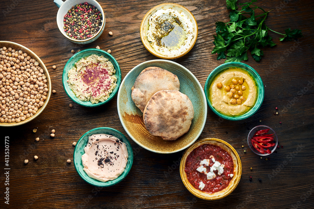 Meze is an oriental set of appetizers served in small bowls with pita on a wooden background. Hummus, yogurt, feta mousse in bowls with bread. View from above Meze is an oriental set of appetizers served in small bowls with pita on a wooden background. Hummus, yogurt, feta mousse in bowls with bread. View from above