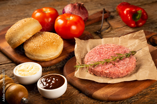 Table with ingredients for hamburger. Raw hamburger.