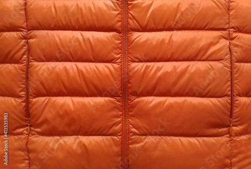 Down jacket fabric background, orange puffer jacket texture photo