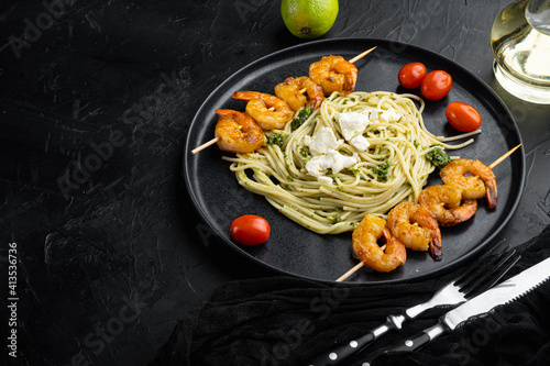 Zuccini spaghetti pasta with pesto and parmesan and prawns, on plate, on black background , with copyspace and space for text
