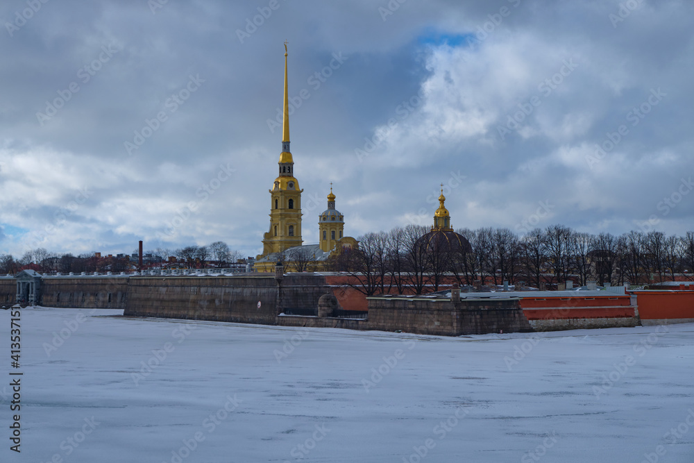 Peter and Paul fortress and cathedral in St Petersburg, Russia. Cloudy winter day. The Neva river covered with ice and snow. Peter and Paul fortress and cathedral in St Petersburg, Russia. Cloudy winter day. The Neva river covered with ice and snow.