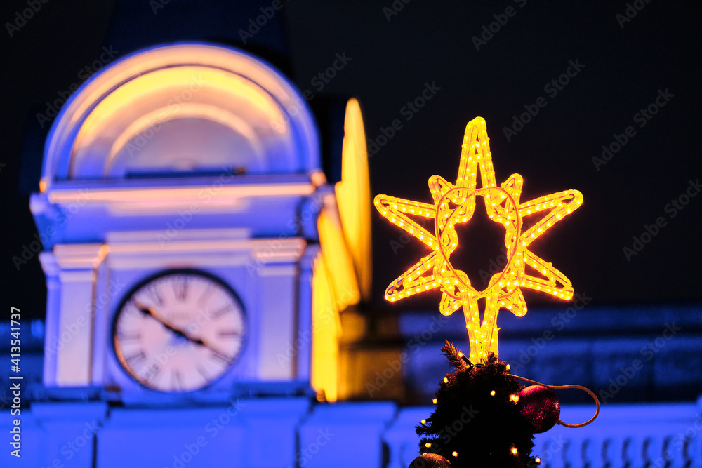 The Christmas star on the background of the dome clock, the building lighted with blue and yellow light.