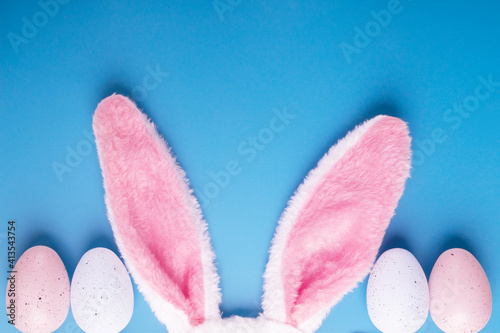 Easter background, eggs in pastel colors and bunny ears on blue