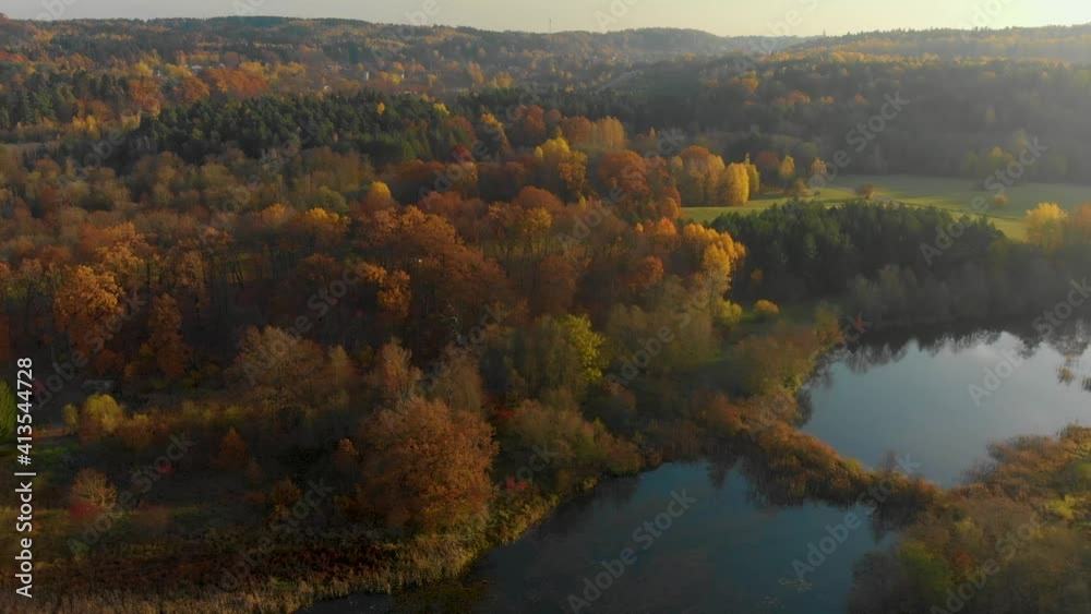 Birds eye view of autumn forest and a small lake. Aerial colorful forest scene in autumn with orange and yellow foliage. Fall scenery in Vilnius, Lithuania Birds eye view of autumn forest and a small lake. Aerial colorful forest scene in autumn with orange and yellow foliage. Fall scenery in Vilnius, Lithuania