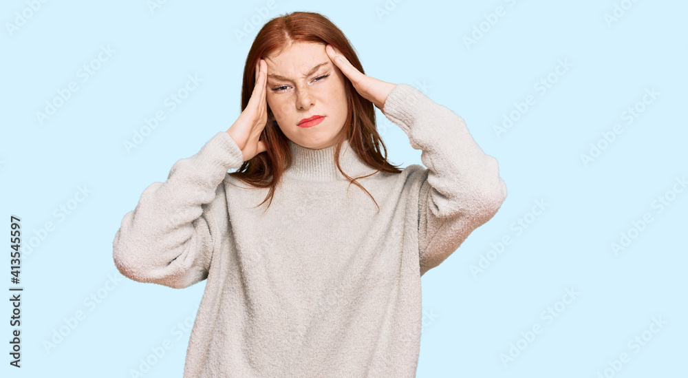 Young read head woman wearing casual winter sweater suffering from headache desperate and stressed because pain and migraine. hands on head. Young read head woman wearing casual winter sweater suffering from headache desperate and stressed because pain and migraine. hands on head.