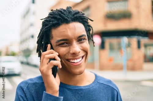 Young african american man smiling happy talking on the smartphone at street of city.
