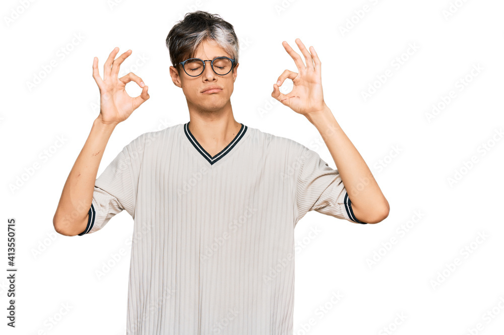 Young hispanic man wearing casual clothes and glasses relax and smiling with eyes closed doing meditation gesture with fingers. yoga concept. Young hispanic man wearing casual clothes and glasses relax and smiling with eyes closed doing meditation gesture with fingers. yoga concept.