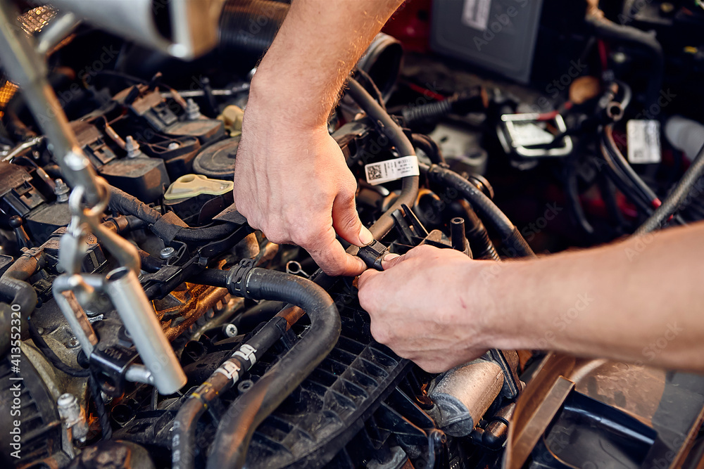 Repairing a car engine in auto-service center. Auto mechanic working in the garage