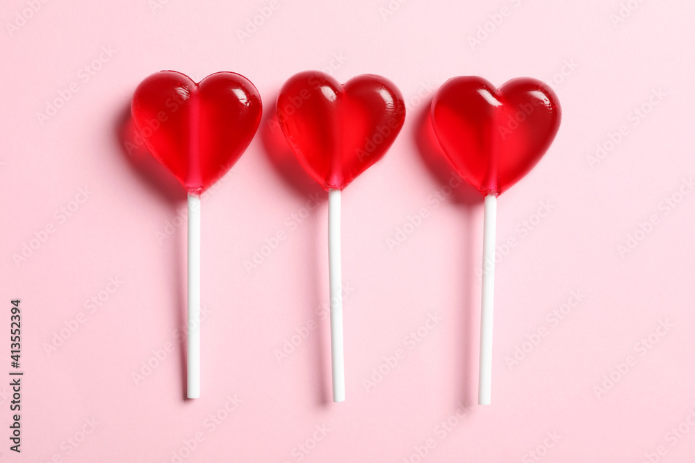 Sweet heart shaped lollipops on pink background, flat lay. Valentine's day celebration