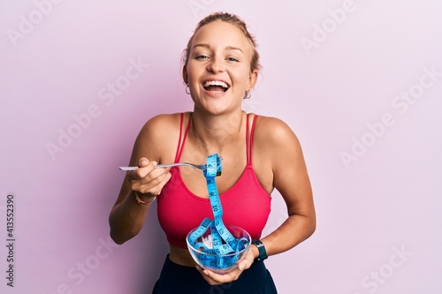 Foto Beautiful caucasian woman eating measure meter doing diet for weight loss smiling and laughing hard out loud because funny crazy joke