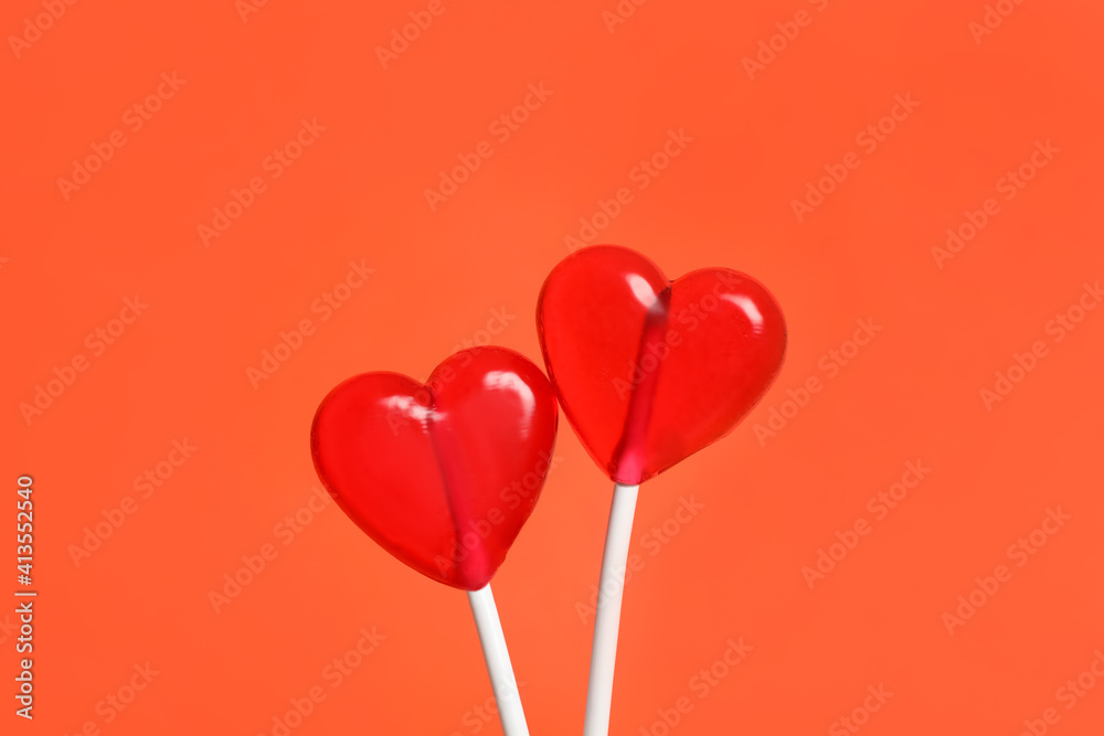 Sweet heart shaped lollipops on coral background, closeup. Valentine's day celebration