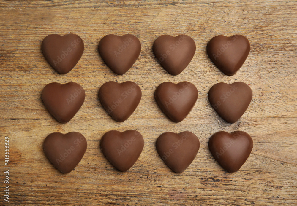 Tasty heart shaped chocolate candies on wooden table, flat lay. Happy Valentine's day Tasty heart shaped chocolate candies on wooden table, flat lay. Happy Valentine's day