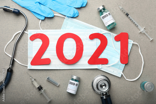 Flat lay composition with coronavirus vaccine and number 2021 on grey background