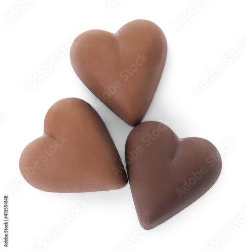 Tasty heart shaped chocolate candies on white background, top view. Valentine's day celebration
