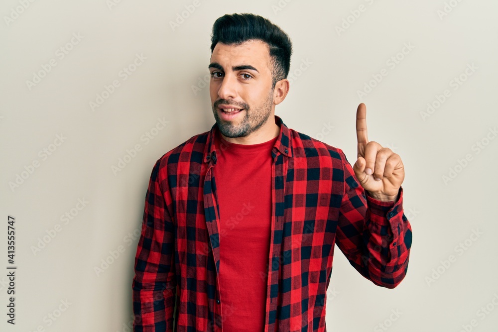 Young hispanic man wearing casual clothes smiling with an idea or question pointing finger up with happy face, number one Young hispanic man wearing casual clothes smiling with an idea or question pointing finger up with happy face, number one