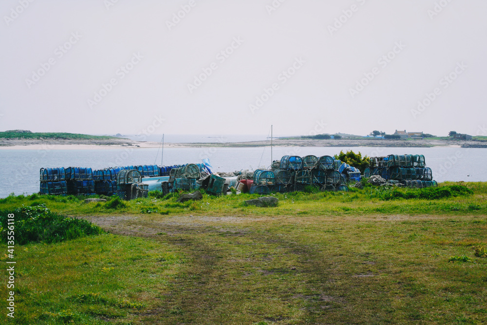 lobster cages on green grass and ocean behind in Brittany, France