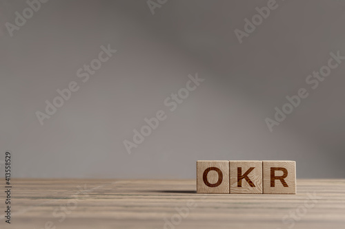 Wood cubes with acronym 'OKR' - 'Objectives and Key Results' on a beautiful wooden table, studio background. Business concept and copy space. photo