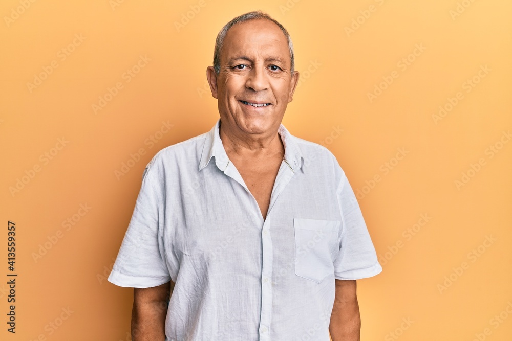 Handsome mature man wearing casual white shirt looking positive and happy standing and smiling with a confident smile showing teeth Handsome mature man wearing casual white shirt looking positive and happy standing and smiling with a confident smile showing teeth