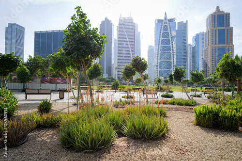 Vue sur un parc urbain au centre de Dubaï avec verdure au premier plan et des gratte-ciel en arrière plan. 