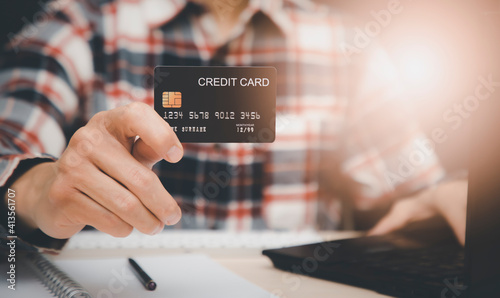Businessman holding credit card and using laptop computer. Online shopping concept,banking and online shopping at the home.Close up.