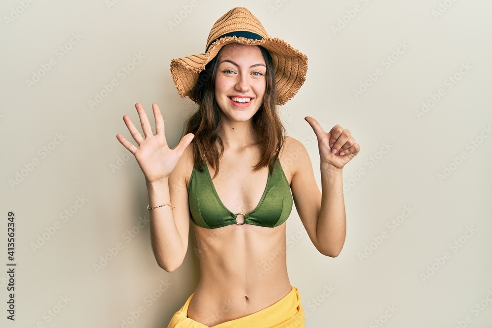 Young brunette woman wearing bikini showing and pointing up with fingers number six while smiling confident and happy. Young brunette woman wearing bikini showing and pointing up with fingers number six while smiling confident and happy.
