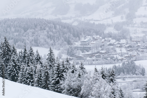Down in the valley lies the famous Kitzbuhel ski resort. After a heavy snowfall, the entire valley, surrounded by a coniferous forest, is covered with 