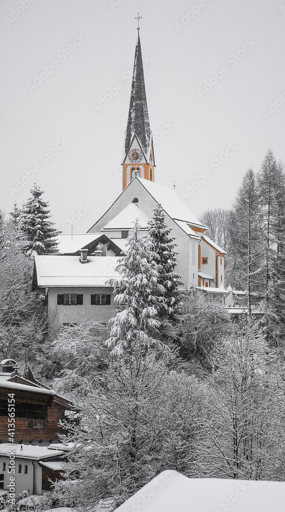 The ski-friendly town of Kirchberg, located on the outskirts of Kitzbuhel. In the middle of hotels and shops, surrounded by snow-covered fir trees, stands a pointed church.