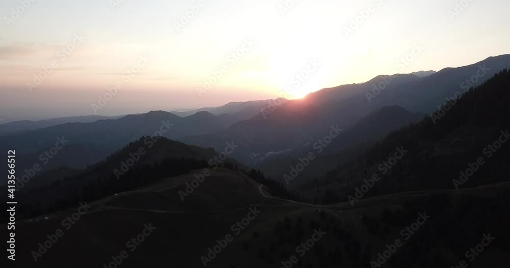 Dawn in the green mountains. High hills covered with grass and forest. Coniferous trees cast shadows from the sun. Trails and tents are visible. View from the drone from above. Kok Zhailau Mountains. Dawn in the green mountains. High hills covered with grass and forest. Coniferous trees cast shadows from the sun. Trails and tents are visible. View from the drone from above. Kok Zhailau Mountains.
