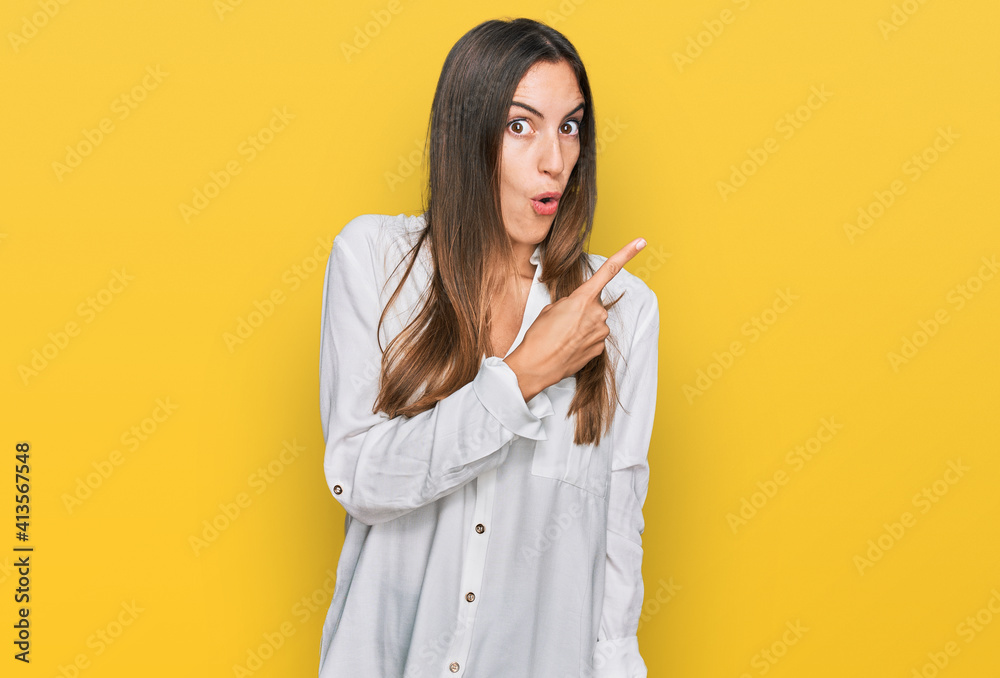 Young beautiful woman wearing casual clothes surprised pointing with finger to the side, open mouth amazed expression. Young beautiful woman wearing casual clothes surprised pointing with finger to the side, open mouth amazed expression.