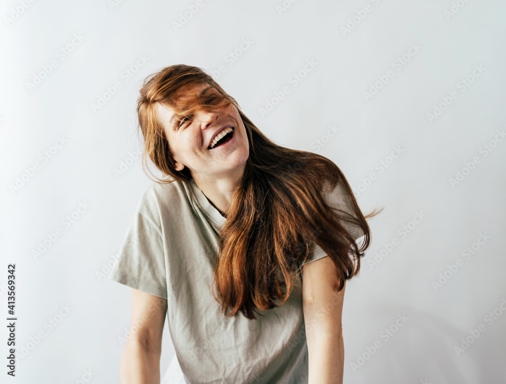 Happy laughing long-haired redhead young woman in a casual T-shirt on a white background. Happy laughing long-haired redhead young woman in a casual T-shirt on a white background.