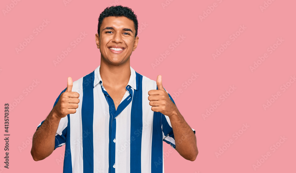 Young arab man wearing casual clothes success sign doing positive gesture with hand, thumbs up smiling and happy. cheerful expression and winner gesture. Young arab man wearing casual clothes success sign doing positive gesture with hand, thumbs up smiling and happy. cheerful expression and winner gesture.