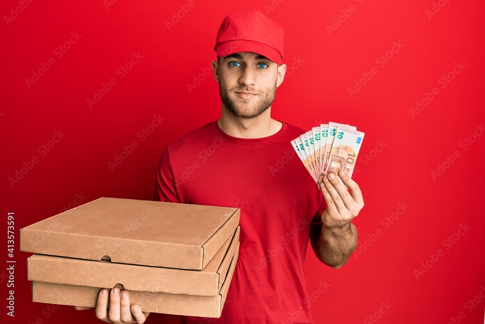 Young caucasian man holding take away food and 10 euros banknotes relaxed with serious expression on face. simple and natural looking at the camera. Young caucasian man holding take away food and 10 euros banknotes relaxed with serious expression on face. simple and natural looking at the camera.