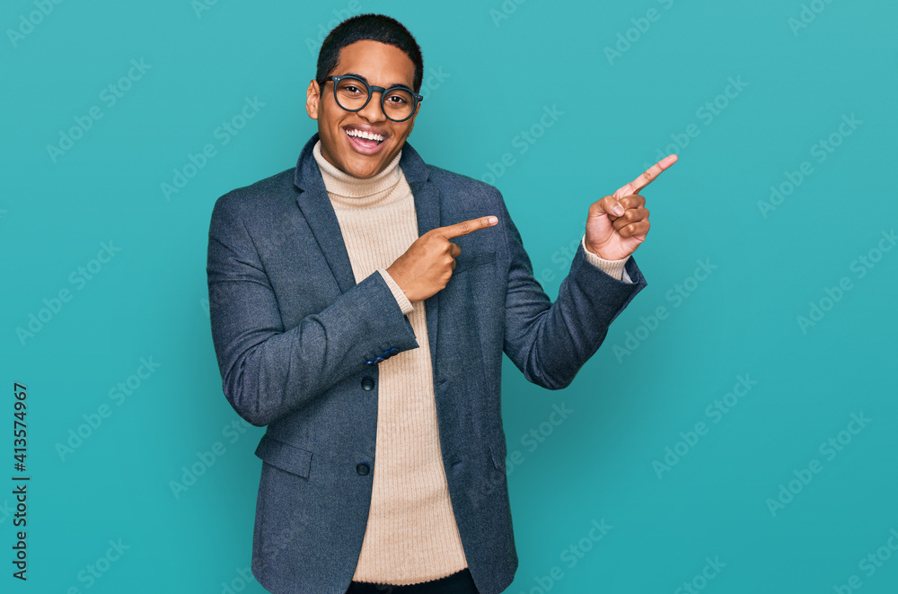 Young handsome hispanic man wearing business jacket and glasses smiling and looking at the camera pointing with two hands and fingers to the side. Young handsome hispanic man wearing business jacket and glasses smiling and looking at the camera pointing with two hands and fingers to the side.