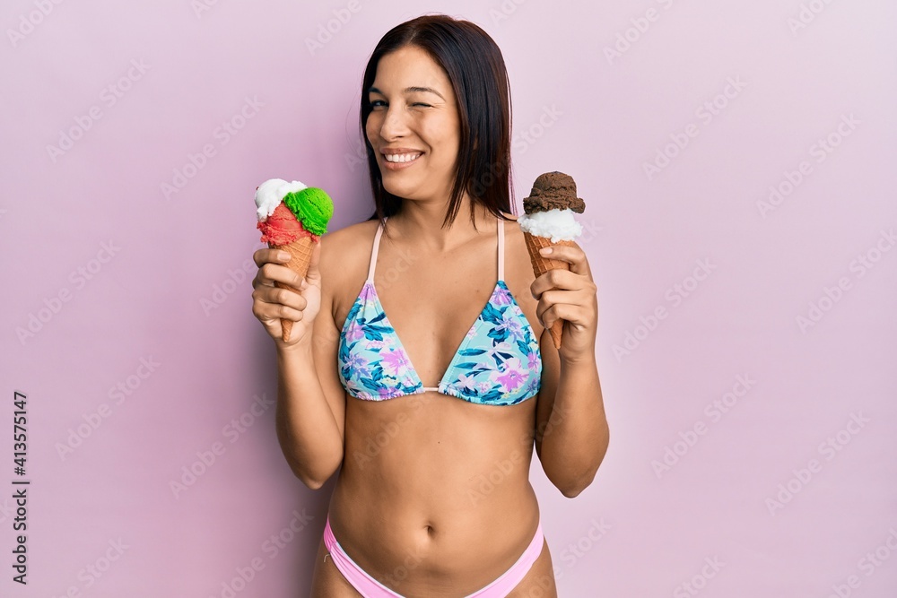 Overgave onze roem Stockfoto Young latin woman wearing bikini holding ice cream winking  looking at the camera with sexy expression, cheerful and happy face. |  Adobe Stock