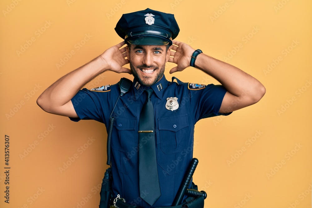 Handsome hispanic man wearing police uniform relaxing and stretching, arms and hands behind head and neck smiling happy Handsome hispanic man wearing police uniform relaxing and stretching, arms and hands behind head and neck smiling happy