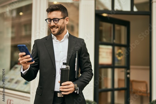 Young hispanic businessman smiling happy using smartphone at the city.