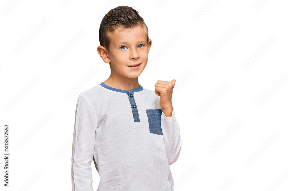 Adorable caucasian kid wearing casual clothes smiling with happy face looking and pointing to the side with thumb up. Adorable caucasian kid wearing casual clothes smiling with happy face looking and pointing to the side with thumb up.