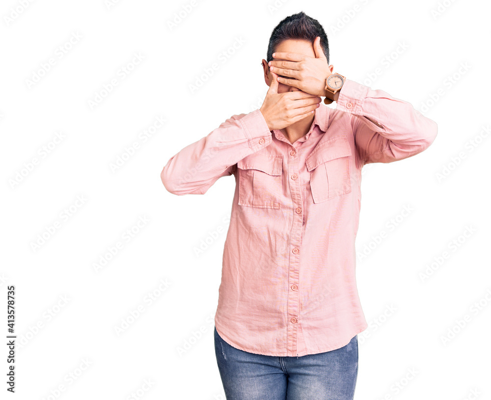 Young woman with short hair wearing casual clothes covering eyes and mouth with hands, surprised and shocked. hiding emotion Young woman with short hair wearing casual clothes covering eyes and mouth with hands, surprised and shocked. hiding emotion