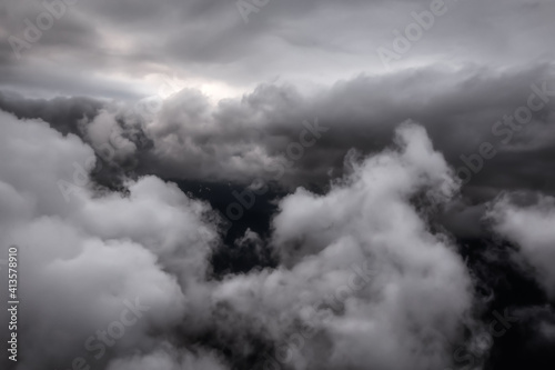 Cloudscape Background. Beautiful and striking aerial view of the puffy clouds. Dramatic Dark Art Render. Taken over the mountains from airplane near Vancouver, British Columbia, Canada.