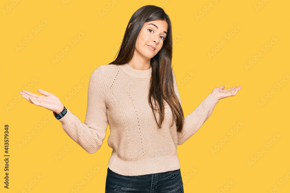 Young brunette woman wearing casual winter sweater clueless and confused expression with arms and hands raised. doubt concept. Young brunette woman wearing casual winter sweater clueless and confused expression with arms and hands raised. doubt concept.