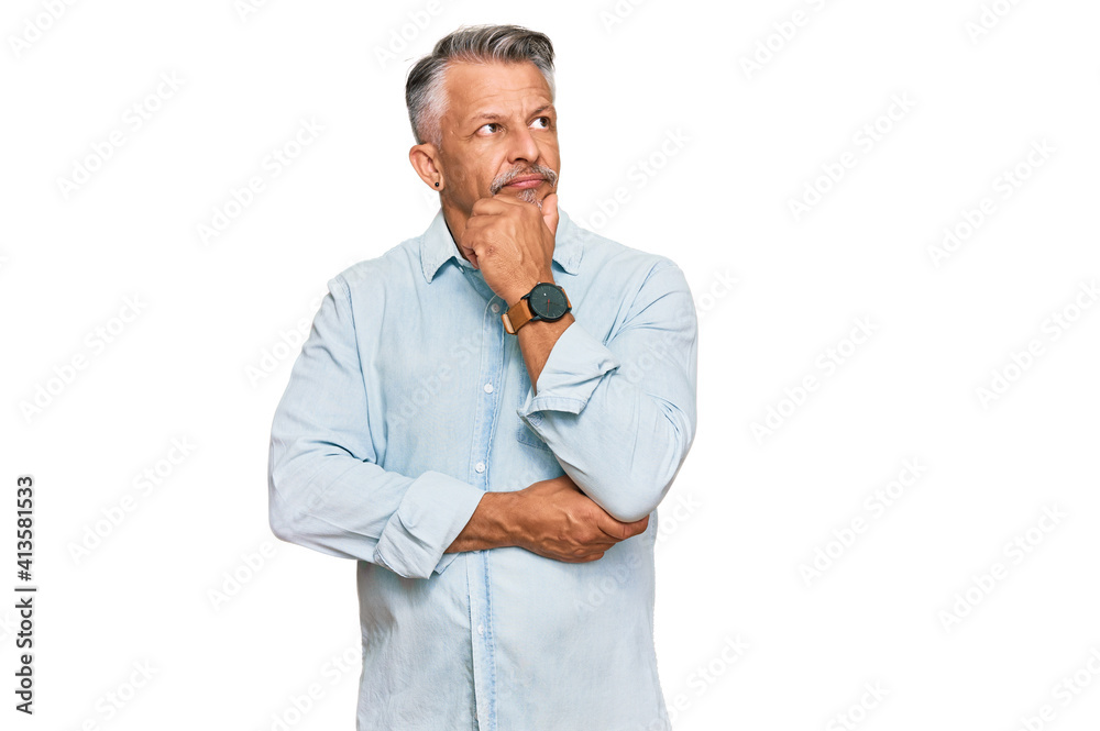 Middle age grey-haired man wearing casual clothes with hand on chin thinking about question, pensive expression. smiling with thoughtful face. doubt concept. Middle age grey-haired man wearing casual clothes with hand on chin thinking about question, pensive expression. smiling with thoughtful face. doubt concept.