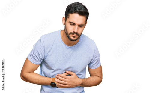 Young hispanic man wearing casual clothes with hand on stomach because indigestion, painful illness feeling unwell. ache concept.