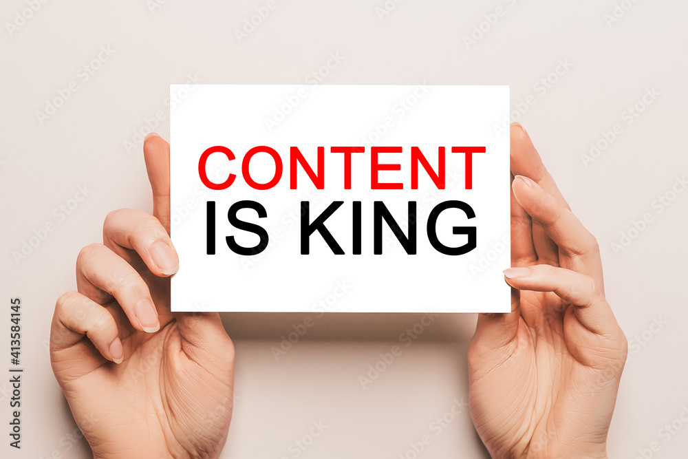 Female hands hold card paper with text Content is King on a yellow background. Business and finance concept Female hands hold card paper with text Content is King on a yellow background. Business and finance concept