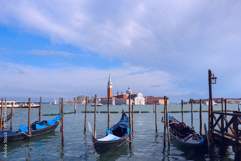Beautiful view of traditional Gondolas moored on San Marco square with historic Basilica of San Giorgio Maggiore in the background