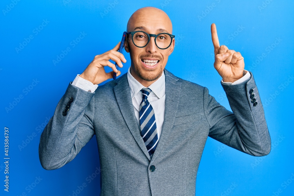 Bald man with beard having conversation talking on the smartphone smiling with an idea or question pointing finger with happy face, number one Bald man with beard having conversation talking on the smartphone smiling with an idea or question pointing finger with happy face, number one