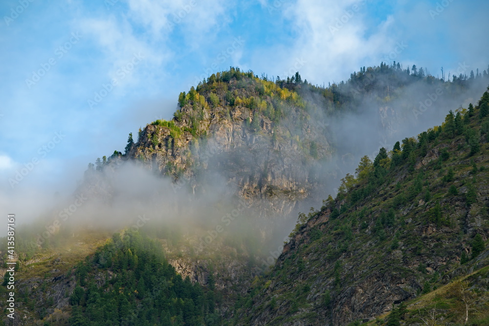 Russia. Mountain Altai. Fog turning into rain clouds around mountain peaks in the Chulyshman River valley in the south of Lake Teletskoye.