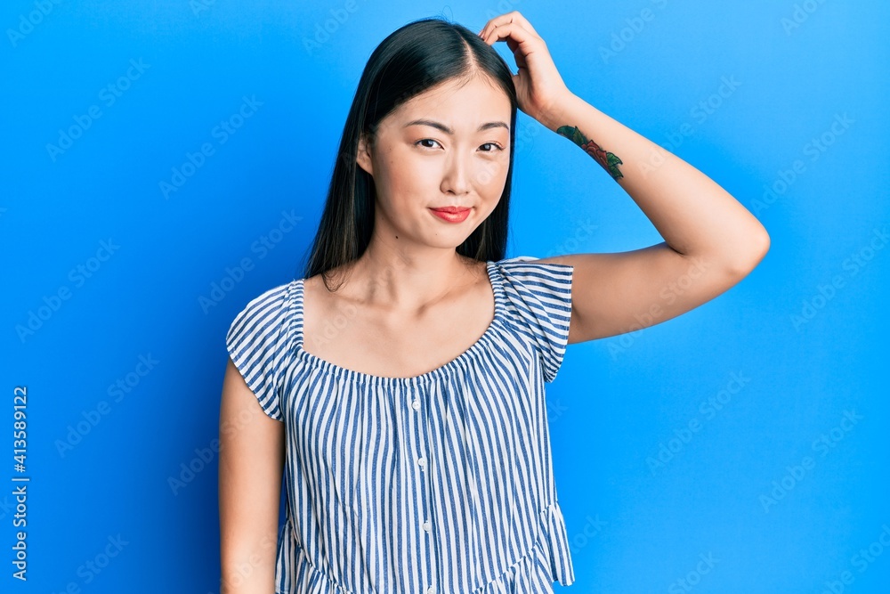 Young chinese woman wearing casual striped t-shirt confuse and wonder about question. uncertain with doubt, thinking with hand on head. pensive concept.