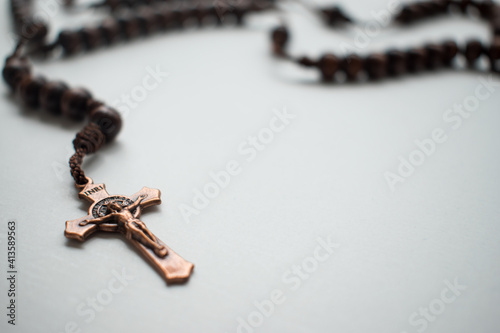 Wooden rosary with metal crucifix on a white surface 